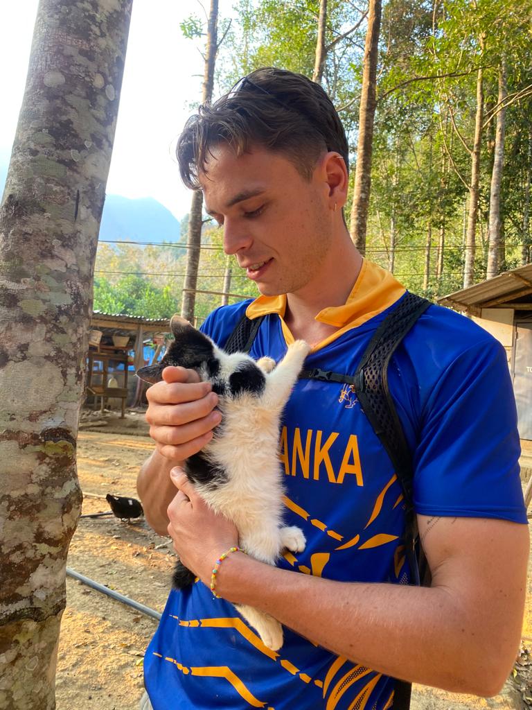 Author of the post holding a small cat in the forest