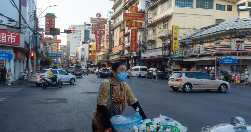 Lady pushing a food cart in the middle of the street in Chinatown, Bangkok.